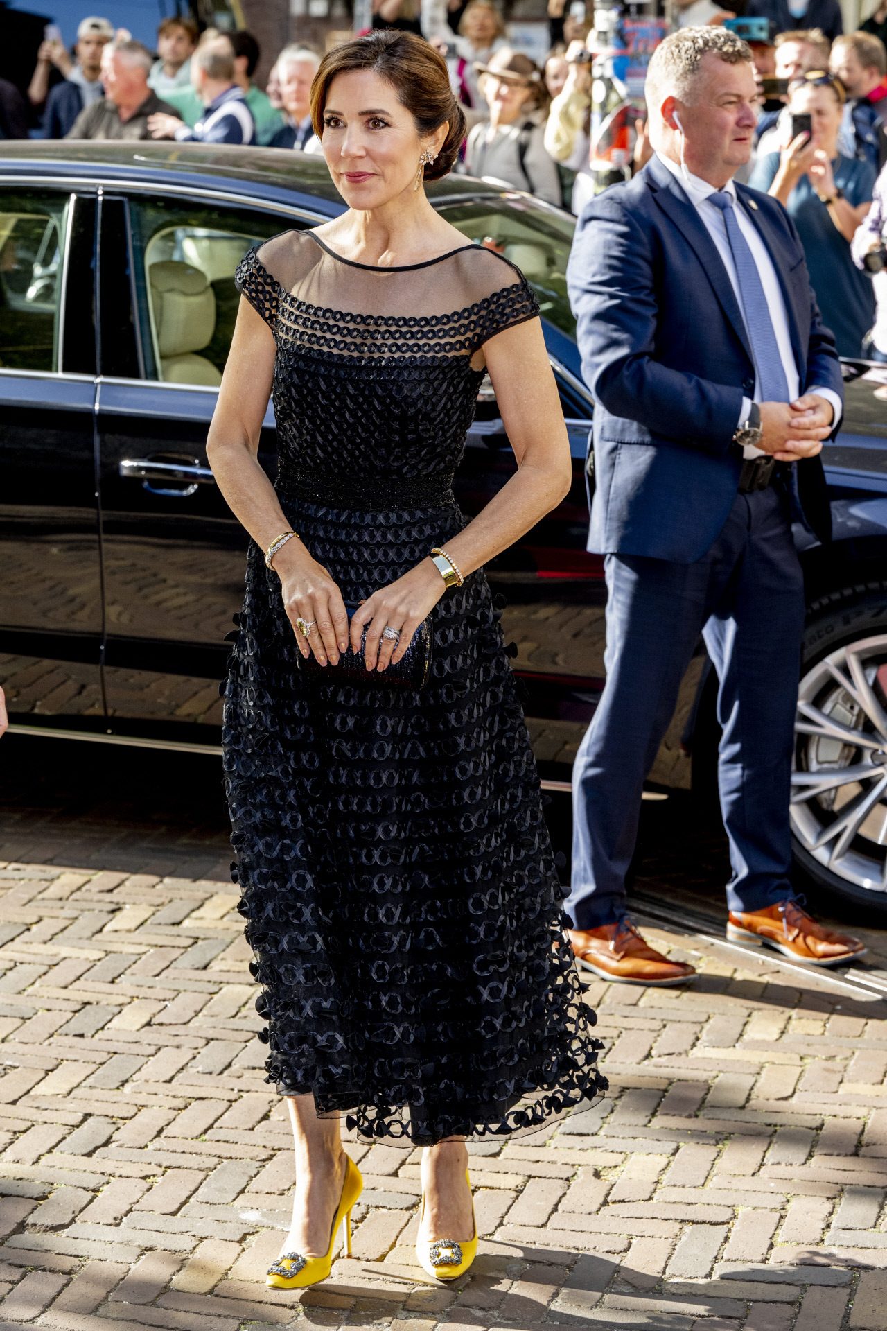 Mary de Donaldson à La Haye dans une robe noire et des chaussures jaunes.