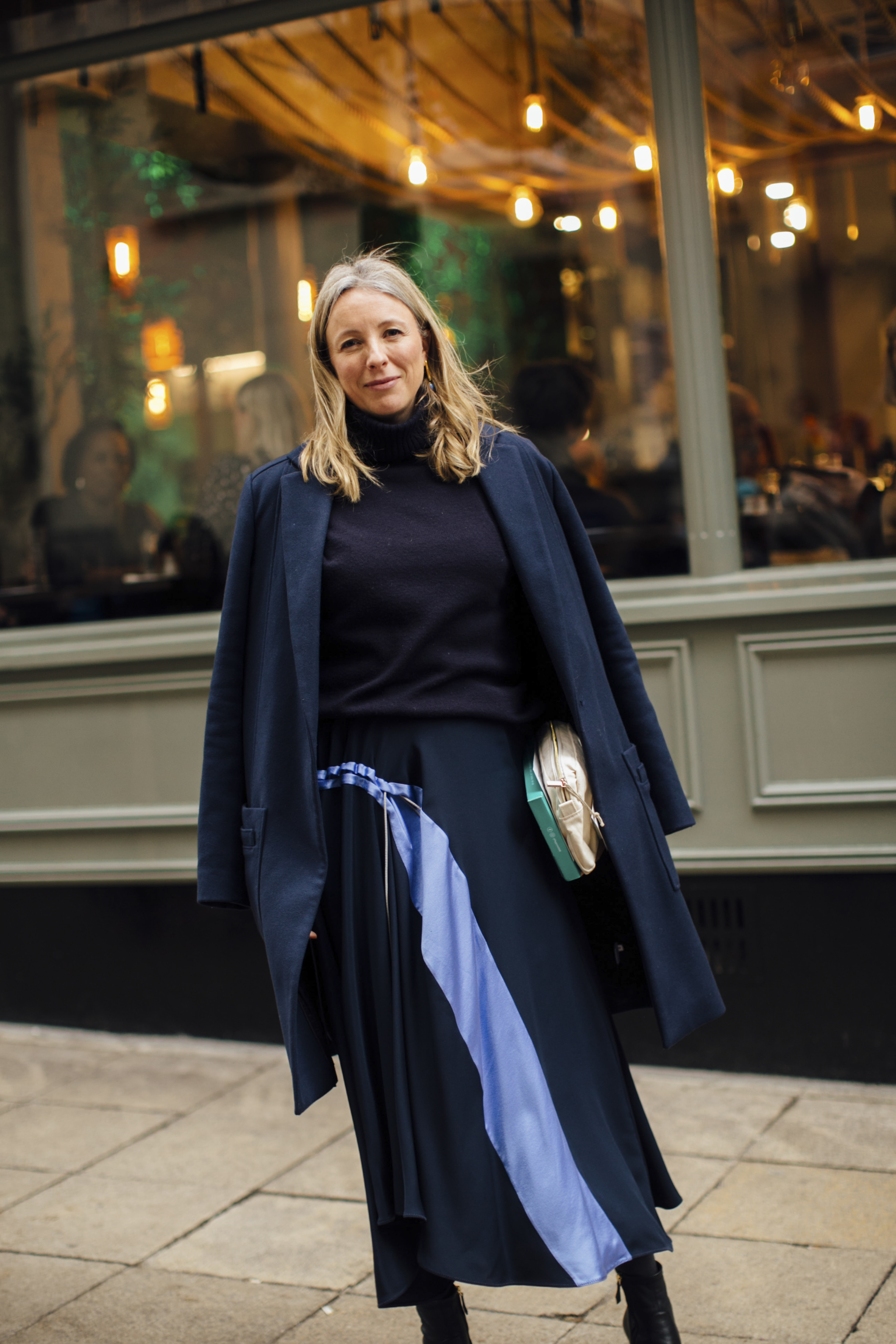 Manteau avec pull et jupe bleu marine.