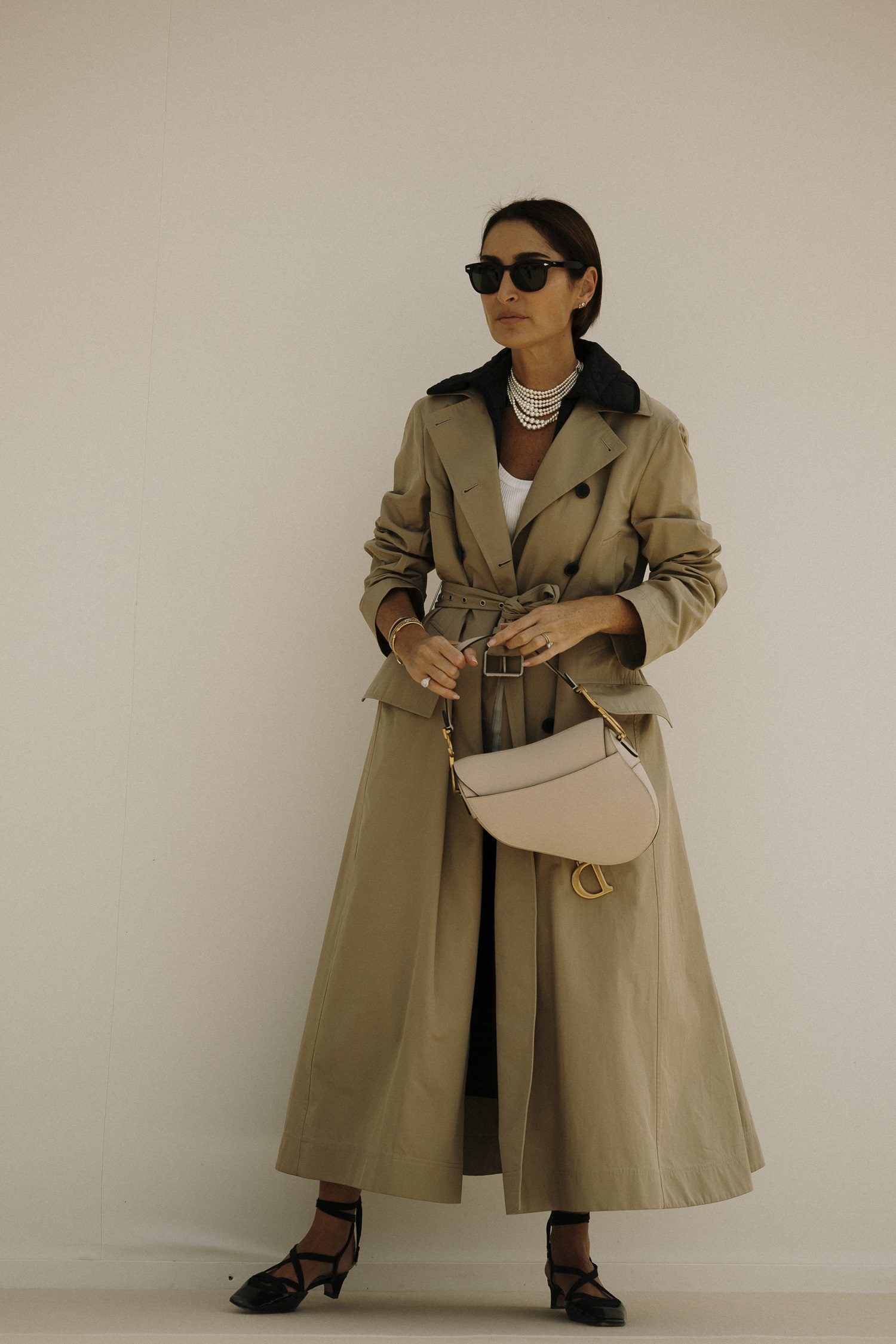 Trench et collier de perles look à la sortie du défilé Dior.