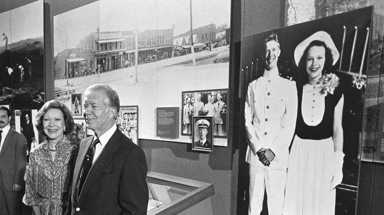 Jimmy Carter et Rosalynn Carter se tiennent devant leur photo de mariage dans un musée