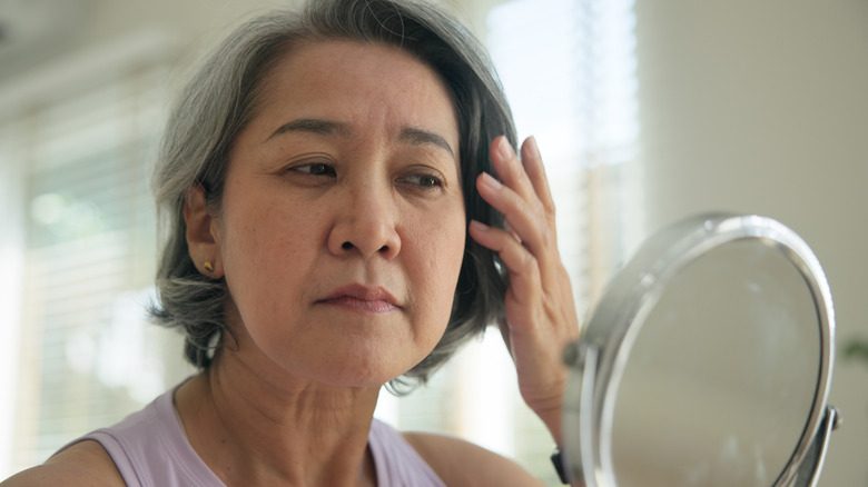 Une femme admirant son travail de Botox autour de ses pieds de cordes dans le miroir