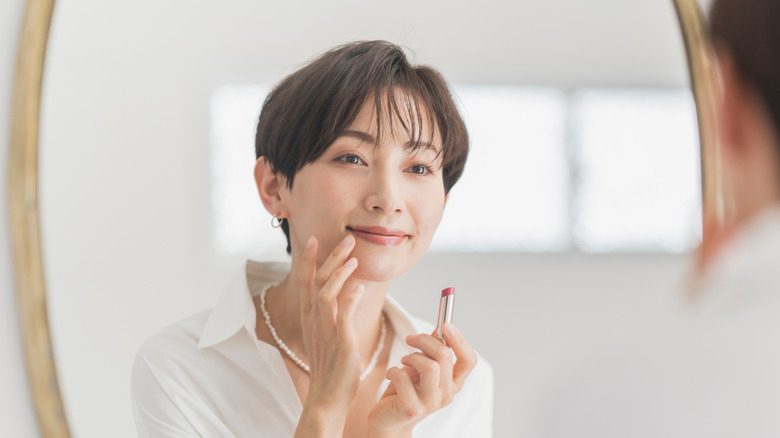 Femme appliquant du rouge à lèvres rose