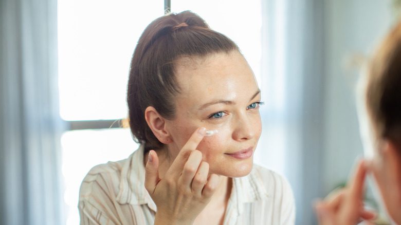 Femme appliquant la crème pour les yeux