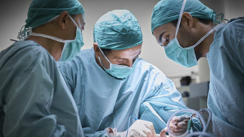 Une équipe de chirurgiens plasticiens exerçant une opération au théâtre