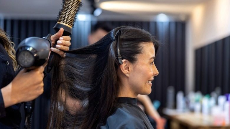 Une femme sourit alors que ses cheveux sont soufflés