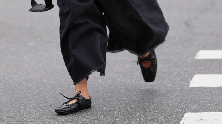 Une femme portant un pantalon noir et des ballets à bout carré noir