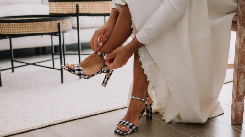 Une mariée choisit une paire de talons à carreaux pour sa tenue de mariage