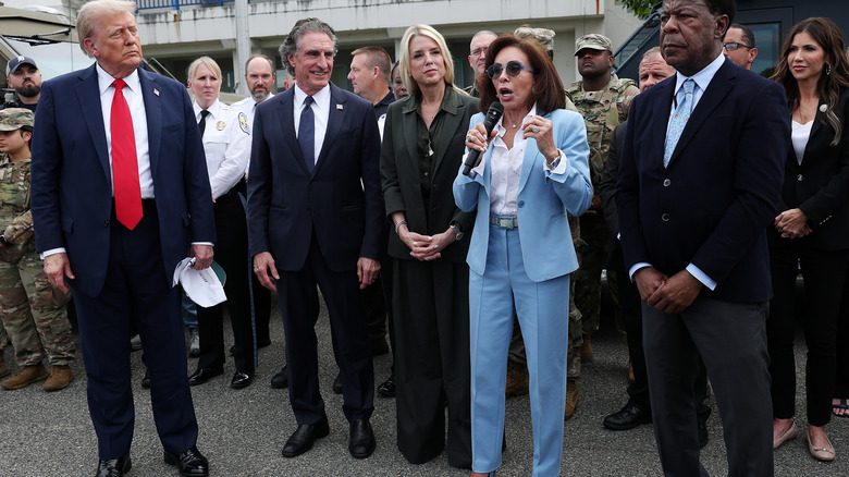 Pam Bondi portant un costume vert ample à côté de Jeanine Pirro et Donald Trump