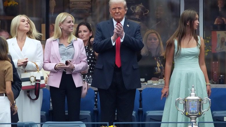 Pam Bondi portant une veste de costume rose avec un pantalon noir et une chemise rayée