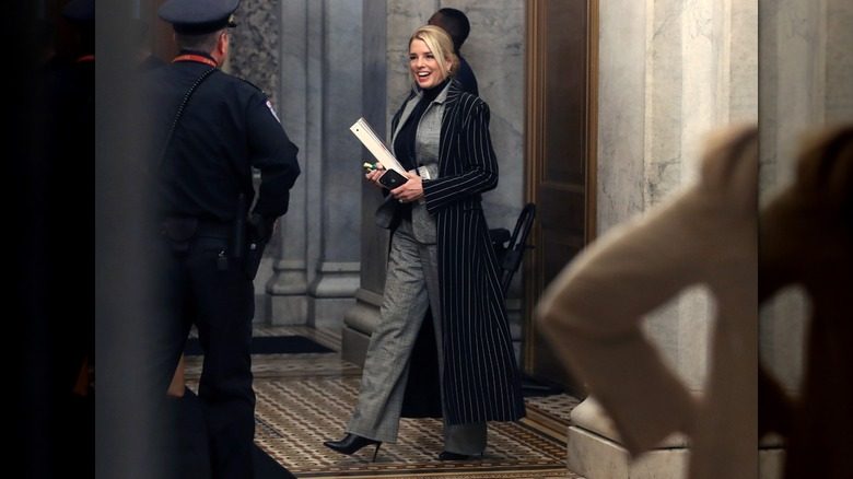 Pam Bondi portant un costume à carreaux et un col roulé et une veste à fines rayures