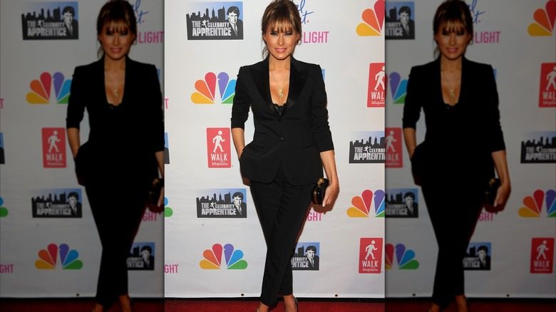 Melania Trump dans une plongeation de pantalon noir debout, les jambes croisées tout en posant pour une photo