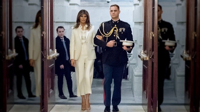 Melania Trump portant un bras de vitesse à pied dans le bras avec un officier du Corps des Marines américain