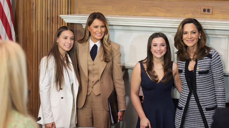 Melania Trump portant un pantalon de ralph lauren sourit alors qu'elle prend une photo avec d'autres dames