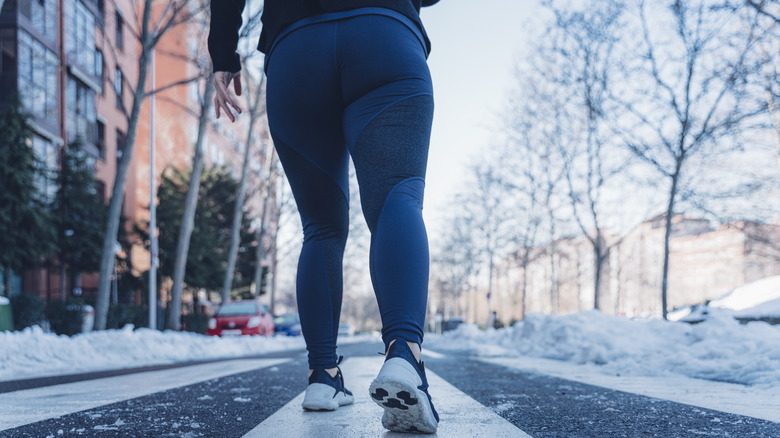 Une personne portant des leggings chauds alors qu'il marche dehors sur une route enneigée