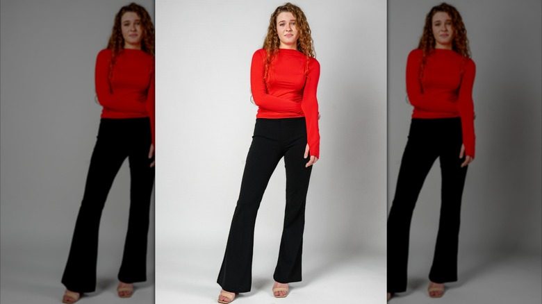 Une fille se tient debout dans une chemise rouge à manches longues et des leggings de poussée noire