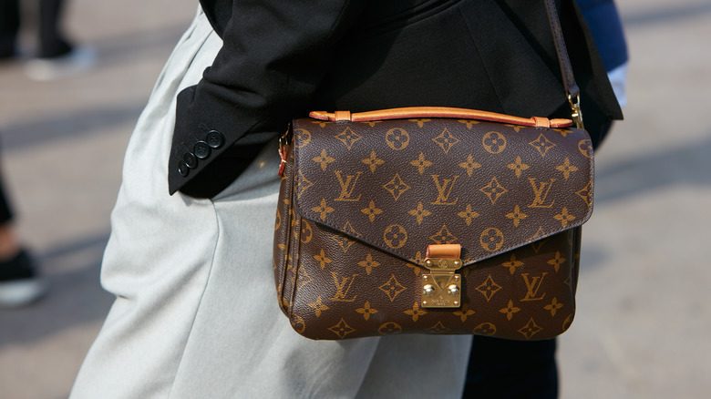 Une personne portant un sac de messager Louis Vuitton