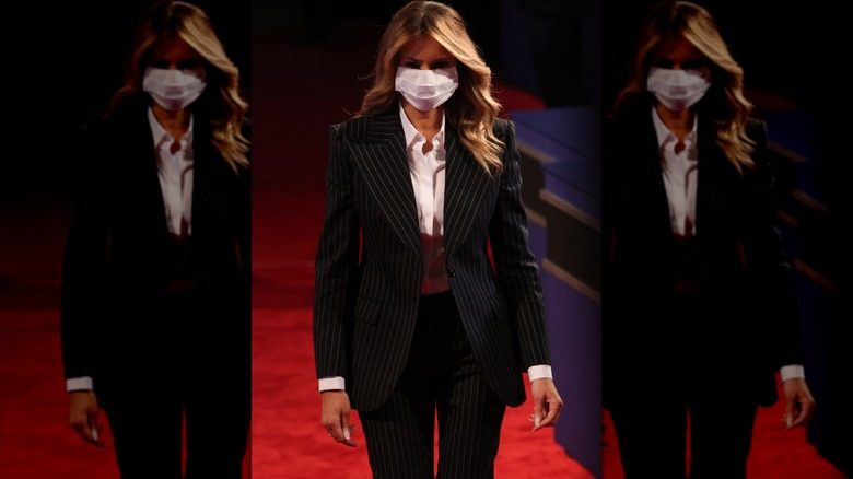 Melania Trump portant un costume à fines rayures en noir et blanc en marchant sur un tapis rouge