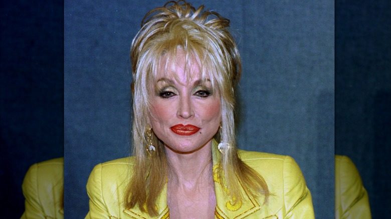 Dolly Parton porte une veste jaune avec des cheveux ébouriffés