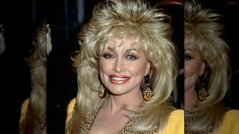 Dolly Parton avec des cheveux à plumes dans une tenue jaune