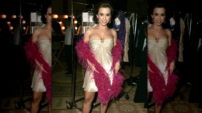 Lacey Chabert pose pour une photo dans une robe de cocktail et un boa