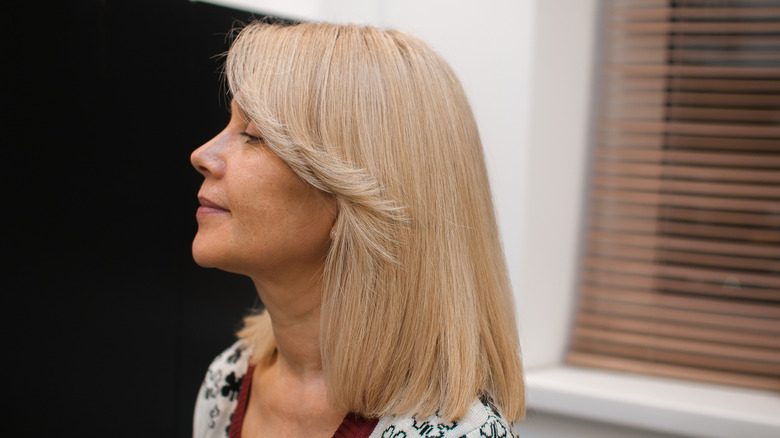 Femme mûre avec lob blond et frange de rideau