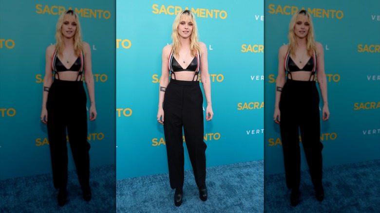 Kristen Stewart posant avec un pantalon, des bretelles et un soutien-gorge en cuir