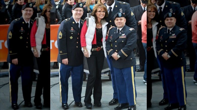 Sarah Palin sourit avec deux officiers tout en portant une doudoune