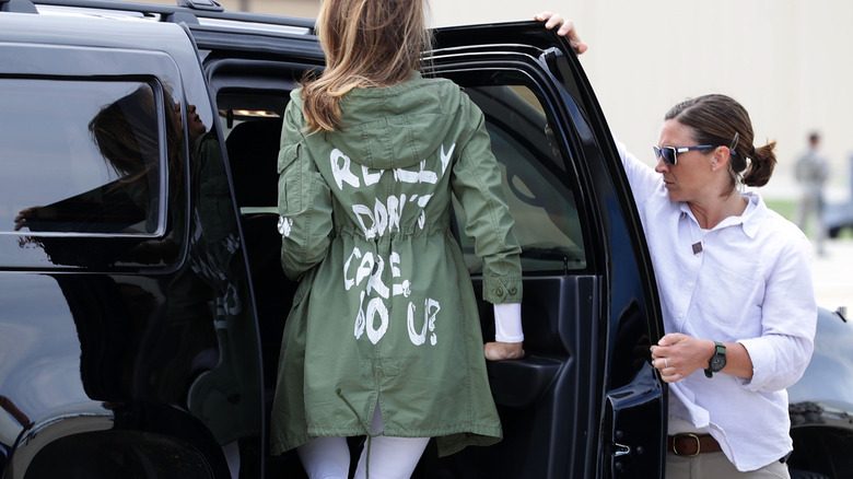 Melania Trump porte une veste avec je m'en fiche vraiment. Et vous ? à l'arrière en entrant dans une voiture