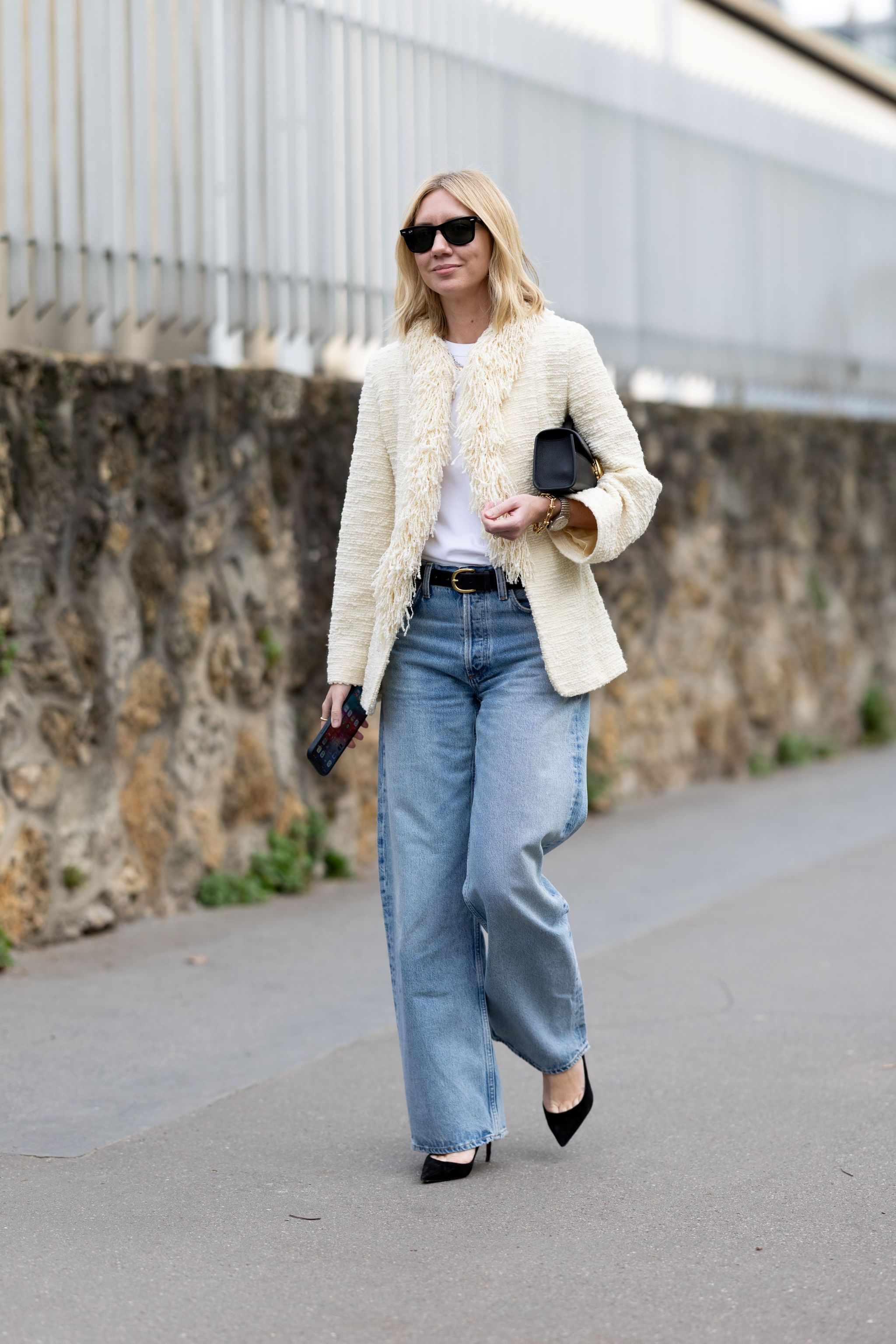 Lisa Aiken dans un t-shirt blanc, un blazer en tweed, un jean baggy et des escarpins noirs.
