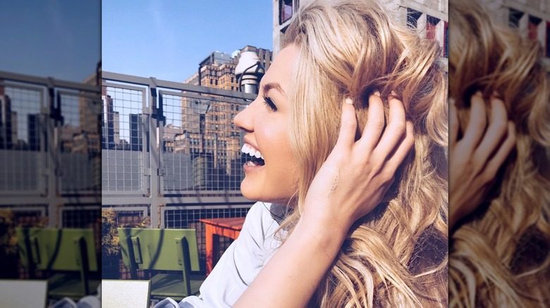 Erika Kirk rit sur un coin salon sur le toit en passant ses doigts dans ses cheveux