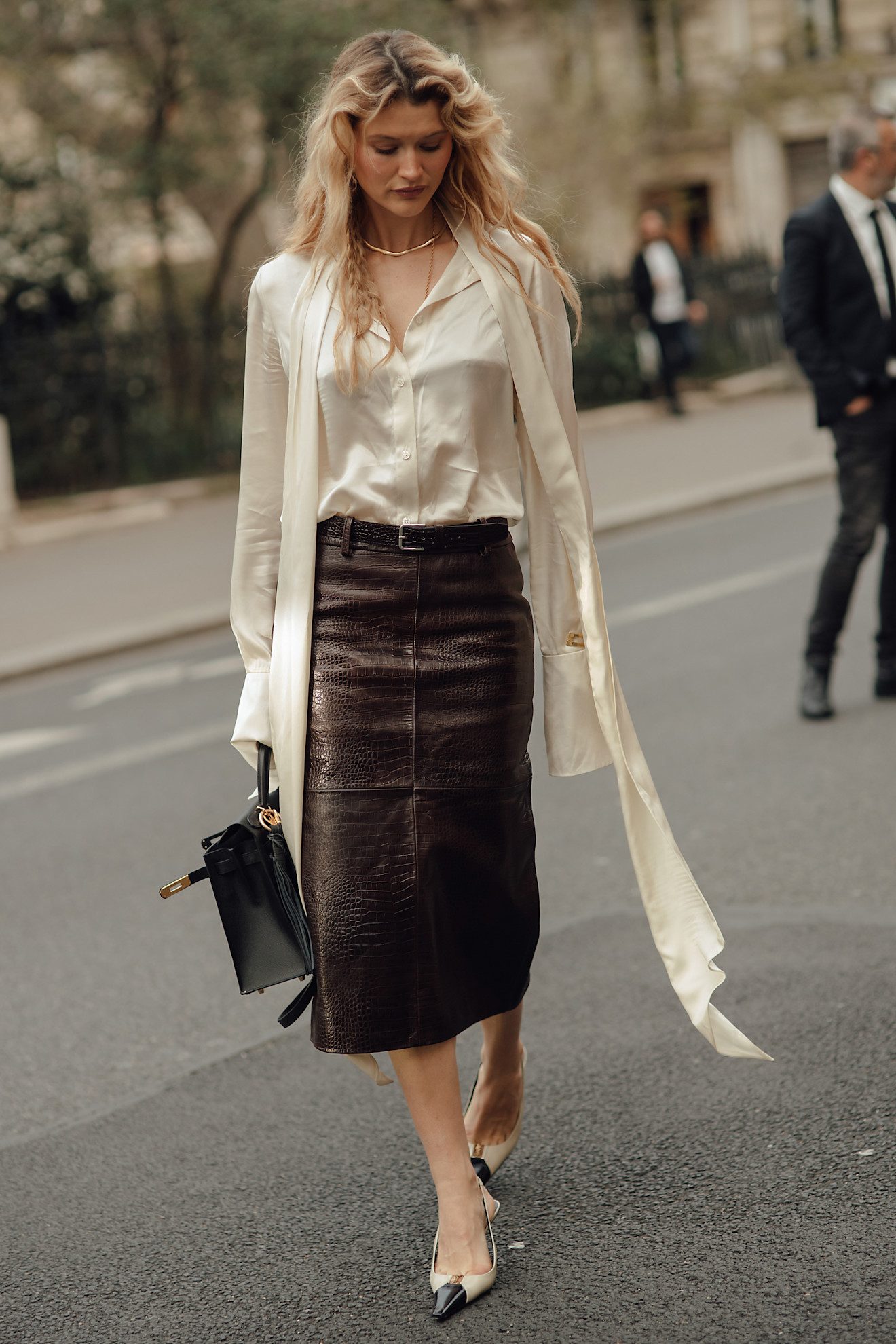 Chemise en satin avec jupe crayon midi en cuir à brides arrière et Hermès Kelly.