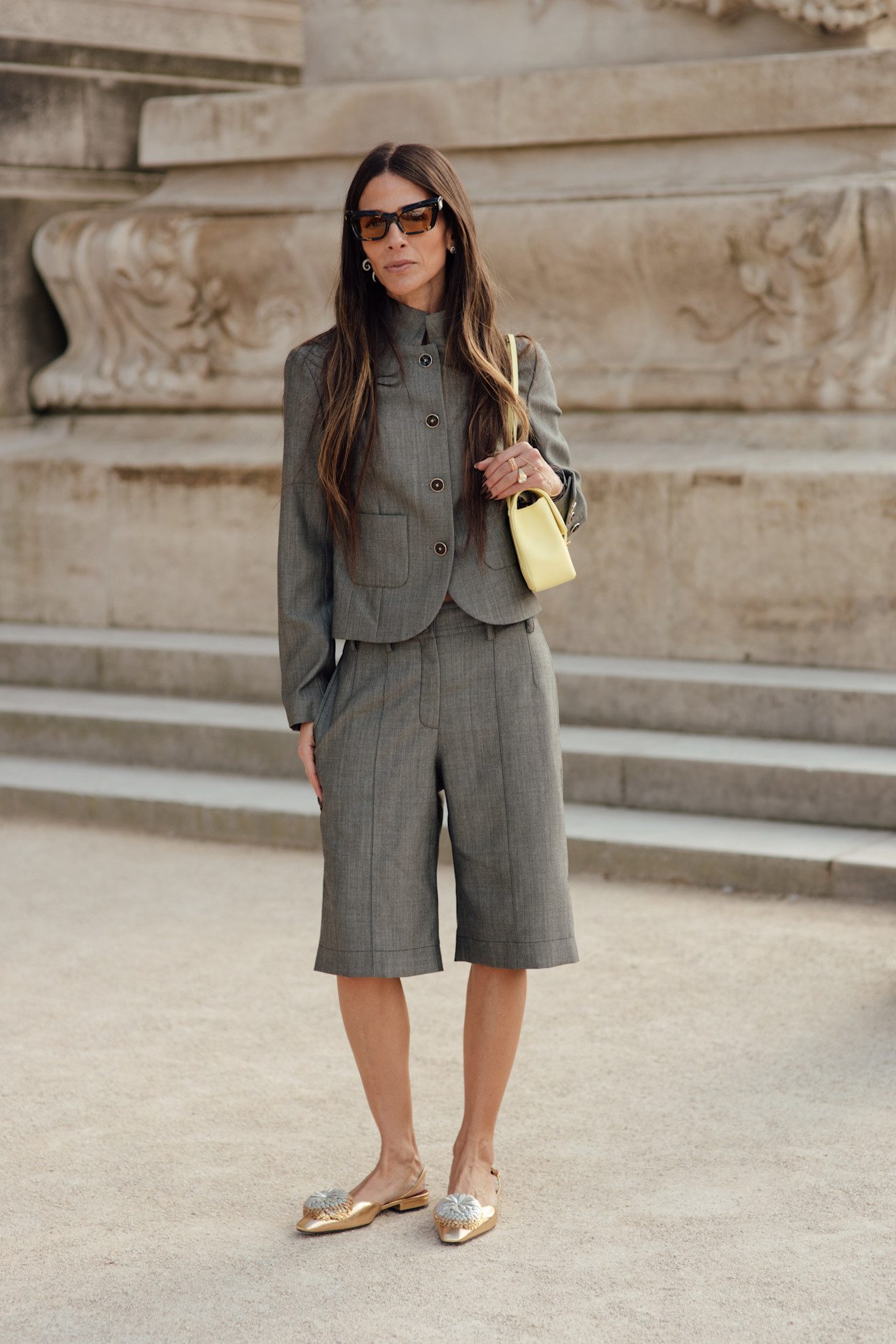 Associez un bermuda gris avec des mules dorées et un sac jaune beurre.