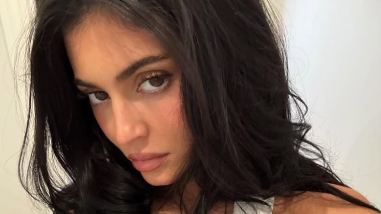 Kyie Jenner avec un look glamour discret et un crop top blanc