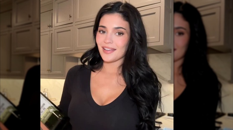Kylie Jenner avec un maquillage sans maquillage tenant une bouteille de Smash Oil