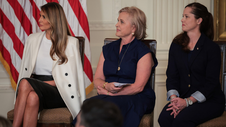 Melania Trump assise dans une jupe en cuir noire et un blazer crème
