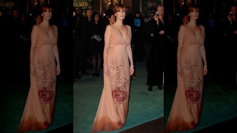Kelly Reilly foule le tapis rouge dans une robe couleur pêche avec des taches d'eau sur le bas de la jupe