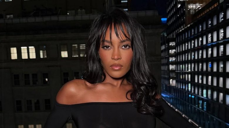 Ciara Miller posant avec des cheveux bouclés et une frange vaporeuse