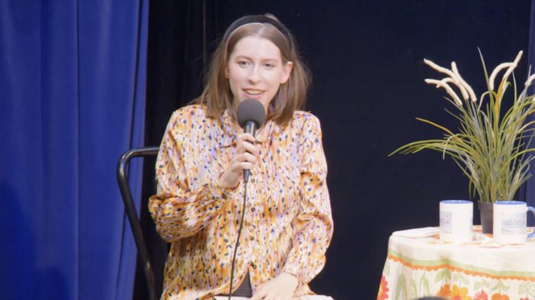 Eden Sher parle dans un microphone alors qu'elle est sur scène pour un spectacle en direct