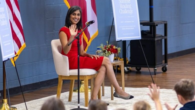 Usha Vance est assise devant une foule d'enfants. Elle porte une longue robe rouge et des ballerines.