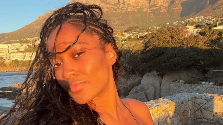 Ciara Miller posant devant l'océan avec des tresses et un look sans maquillage