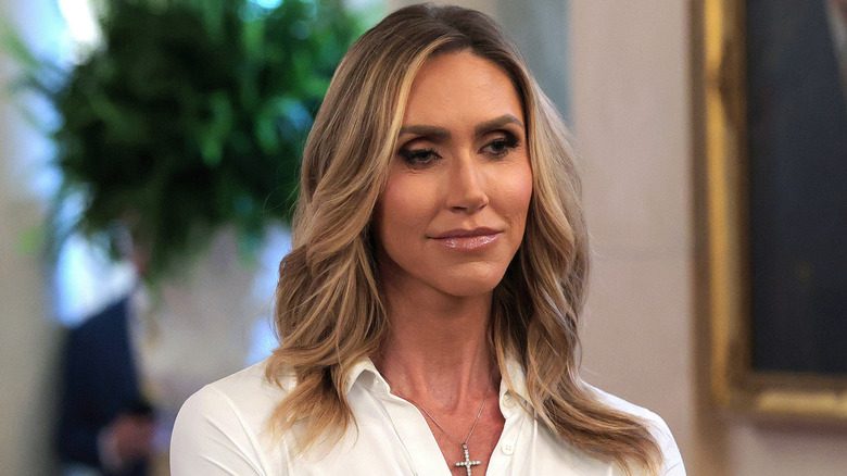 Lara Trump porte une chemise à col blanc et un collier en forme de croix de diamants.