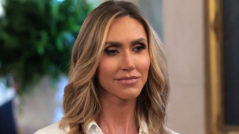 Gros plan sur Lara Trump. Elle a un visage entièrement maquillé, y compris des sourcils foncés, et porte un chemisier boutonné blanc.