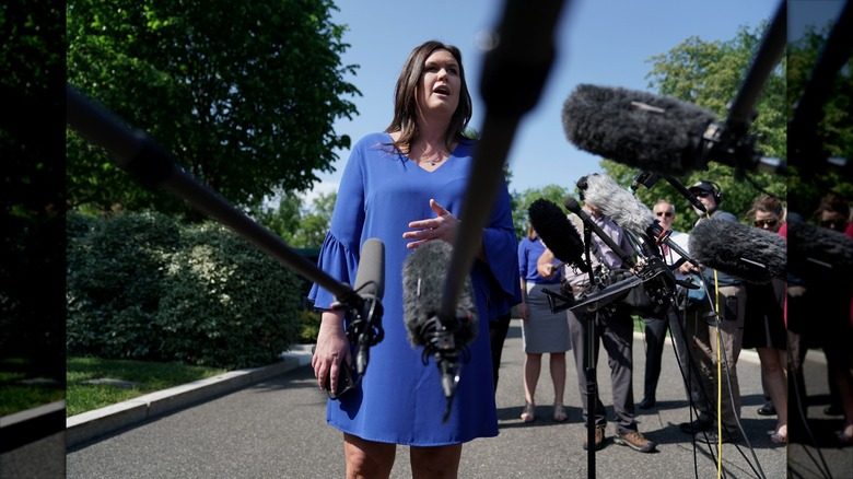 Sarah Huckabee Sanders s'adresse aux journalistes dans une robe droite bleue à manches cloche