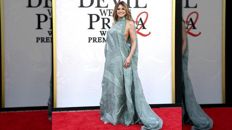 Heidi Klum à la première de DWP2. C'est une femme à la peau claire et aux cheveux blonds. Elle porte une robe sans manches à col montant vert écume de mer avec des découpes latérales révélatrices, des motifs plissés en accordéon et une traîne large et fluide.