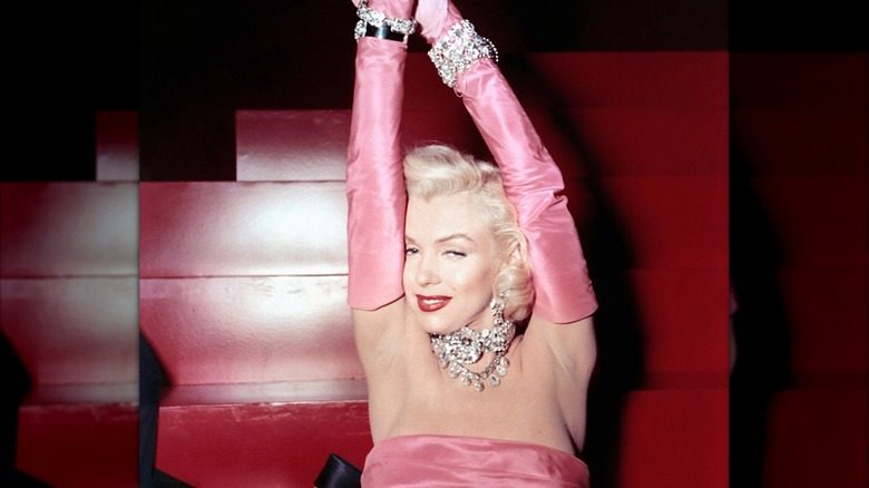 Marilyn Monroe en robe rose avec des gants jusqu'aux coudes, trempée de bijoux pour 