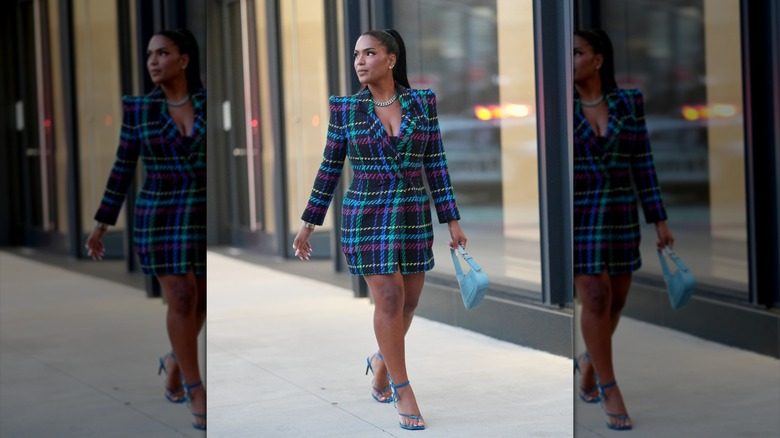 Une femme vêtue d'un manteau à carreaux et de chaussures bleues avec un sac à main bleu