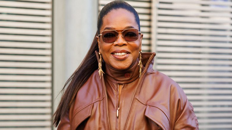 Oprah Winfrey dans une combinaison en cuir et des lunettes de soleil souriante
