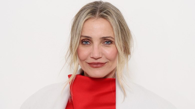 L'acteur Cameron Diaz porte un manteau blanc et une robe à col roulé rouge
