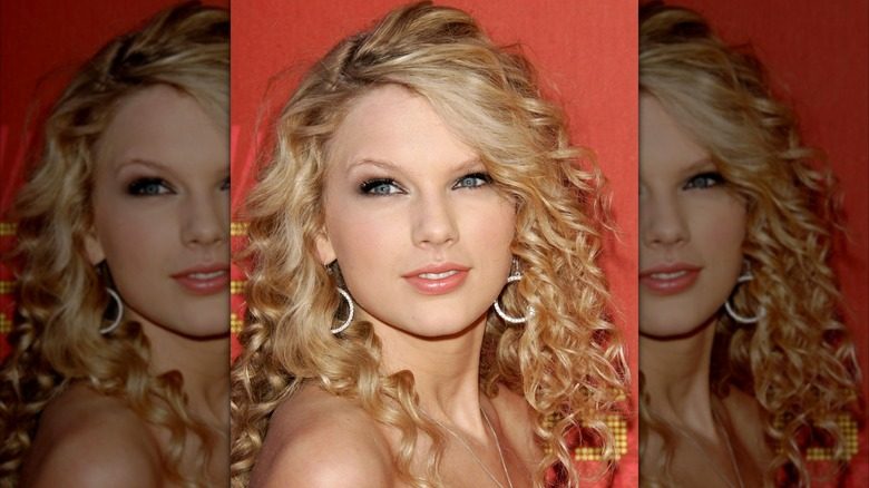 Taylor Swift avec des boucles d'oreilles, des yeux charbonneux et des lèvres nues lors d'un événement sur le tapis rouge en 2007.