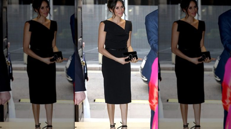 Meghan Markle porte une élégante robe midi noire et une pochette